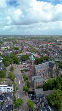 Küçük bir Avrupa kasabasında ağaçlar, evler ve caddelerle çevrili yüksek tuğlalı tarihi bir kilise manzarası. Kırmızı çatıları, yeşil ağaçları olan büyüleyici bir Avrupa kasabasının havadan görünüşü.