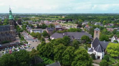 Otoparkı, arabaları, ağaçları ve kaldırımda geometrik desenleri olan bir kasaba meydanının hava aracı görüntüsü şehir tasarımını, günlük yaşamı ve organize şehir yapısını gösteriyor. Güzel kilise..