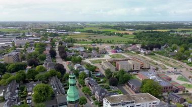 Otoparkı, arabaları, ağaçları ve kaldırımda geometrik desenleri olan bir kasaba meydanının hava aracı görüntüsü şehir tasarımını, günlük yaşamı ve organize şehir yapısını gösteriyor. Güzel kilise..