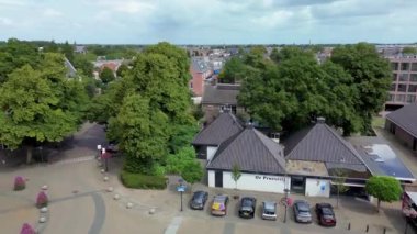 Otoparkı, arabaları, ağaçları ve kaldırımda geometrik desenleri olan bir kasaba meydanının hava aracı görüntüsü şehir tasarımını, günlük yaşamı ve organize şehir yapısını gösteriyor. Güzel kilise..