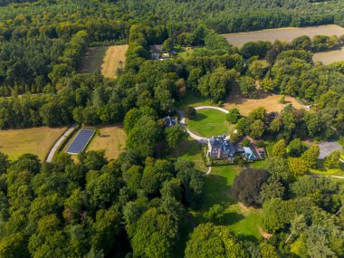 Merkezi malikane, dairesel garaj yolu, bitişik binalar, güneş panelleri ve geleneği, doğayı ve sürdürülebilirliği harmanlayan çevredeki alanların havadan görünüşü.