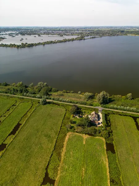 Kırsal arazinin havadan görünüşü, sulama alanları, göl evi, bahçe ve uzak kıyı şeridi ile uyumlu arazi kullanımı ve su yönetimi.