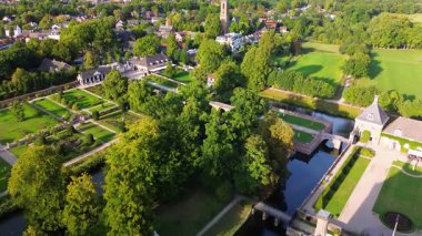 Geometrik planlı, kanal ve ağaçlarla çevrili resmi bir bahçenin havadan görünüşü. Merkezde beyaz bir malikane duruyor, yolları, çitleri ve zarif peyzajlarıyla çevrili..