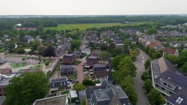 Güneş çatıları, kilise çan kulesi, apartmanlar ve tarım arazisi karışımı gelenek, sürdürülebilirlik ve planlanmış banliyö yaşamına sahip küçük kasaba manzarası..
