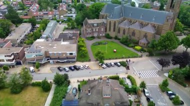 Gotik kilisesiyle şehir manzarası, sazdan çatı, güneş evleri ve yeşil çevrede ikametgah, dini ve toplum mimarisini harmanlayan park edilmiş arabalar..