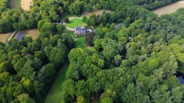 Merkezi malikaneli orman arazisi, manikürlü çimenler, dolambaçlı yollar ve inzivaya çekilmiş tarım arazileri, doğa ve ekilmiş tasarım..