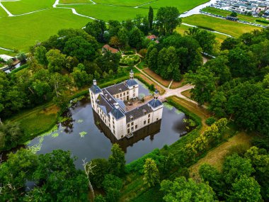 Hendek ve dört köşe kulesi olan, yoğun yeşillik ve tarlalarla çevrili, izolasyon ile manzaralı uyumu harmanlayan kale yapısının havadan görünüşü..