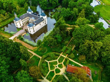 Beyaz kalenin havadan görünüşü, adadaki malikane gibi, hendek, geometrik bahçe, kırmızı çatılı ek bina, ve sık ormanlarda ve açık alanlarda demirlenmiş tekneler, zarafeti doğal ahenkle harmanlıyor..