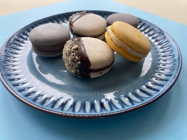 Çikolata ve mavi tabakta renkli kurabiyeler. 