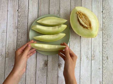 Beyaz ahşap arka planda kavun tutan kadın elleri