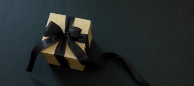 Kara Cuma indirimli afişi. Siyah arka planda siyah kurdeleli hediye kutusu, kopyalama alanı. Noel hediyeleri konsepti.