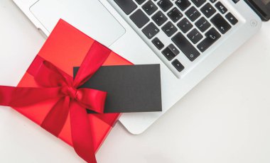 Kırmızı hediye kutusu ve bilgisayar laptopunda siyah kart, beyaz arka plan, üst manzara. Noel hediyeleri Online alışveriş şablonu