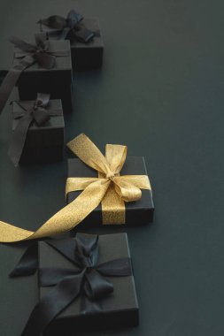 Kara Cuma indirimi ve Noel hediyeleri. Altın kurdeleli hediye kutuları bir, yakın görüş. İyi satın alma, pazarlık konsepti.