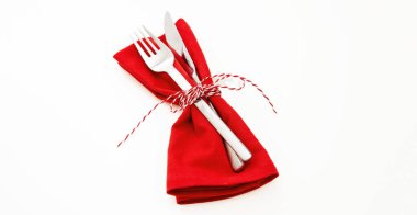 Tatil masası kurma, kutlama yemeği. Çatal bıçak takımı, kırmızı bez peçete ve Noel sicim yayları beyaza izole edilmiş, yakın görüş..