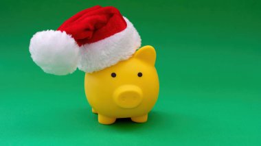 Noel tatili indirimi. Yeşil arka planda izole edilmiş Noel Baba şapkalı domuz kumbarası.
