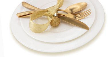 Noel masası manzarayı kapatıyor. Altın çatal bıçak takımı ve beyaz tabaklar, şık bir restoran, kutlama yemeği.