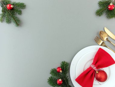 Noel sofrası, kutlama yemeği düzlüğü. Altın çatal bıçak takımı, kırmızı bez peçete ve gri arka planda Xmas süslemesi, üst manzara, kopyalama alanı