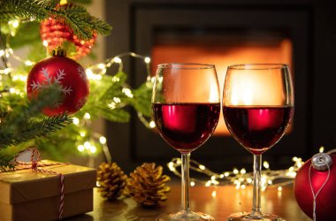 Kırmızı şarap ve Noel süsü, yanan şömine arka planı. Xmas kış tatili kutlaması