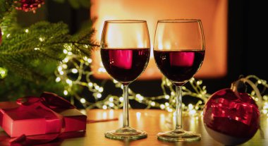 Kırmızı şarap ve Noel süsü, yanan şömine arka planı. Xmas kış tatili kutlaması
