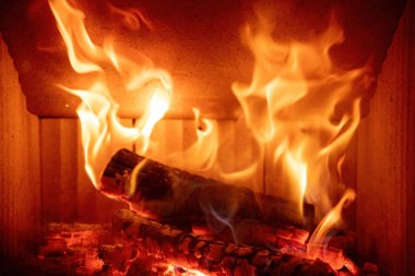 Şömineye yakın, ateş alevi ve yanan odun kütükleri, kışın sıcak ev, ön manzara.