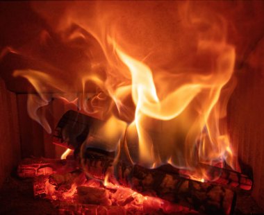 Ateş alevleri ve yanan odun odunları, yakın bir şömine, kışın sıcak bir ev, ön manzara.