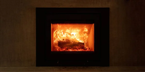 stock image Fire flames and burning wood logs, energy stove fireplace on a wall, warm home in winter, front view