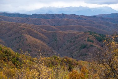 Yunanistan sıra sıra dağlarla çevrili. Çıplak kayalık dalgalı oluşumun panoramik görüntüsü, kışın karlı zirvesi, bulutlu arkaplan. 