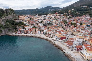Parga, Yunanistan. Geleneksel İyon sahil şehri renkli cephe binalarının ve kayalık tepedeki şatonun insansız hava aracı görüntüsü bulutlu gökyüzü