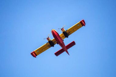 Canadair Firefight Aircraft, Scooper flying on blue sky background, under view. Yellow red color seaplane flight for rescue and transport.