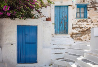 Yunanistan. Tinos sanat adası, Pyrgos köyündeki Cycladic mimarisi, begonvillea beyazlatılmış duvar, mavi kapı ve pencereler, güneşli gün.