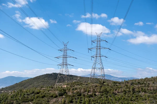 stock image High voltage power lines and pylons on mountain, blue sky background