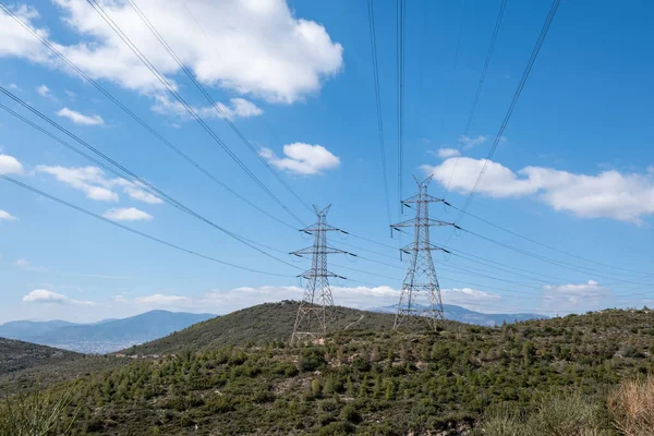 stock image High voltage power lines and pylons on mountain, blue sky background