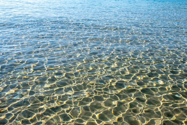 透明平静的蓝色海水背景 阳光反射在海洋上 使其闪闪发光 在海面上闪闪发光 并使海床沙化 — 图库照片
