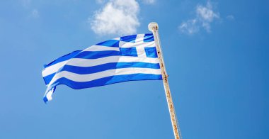 Yunanistan 'ın işareti. Rüzgarda dalgalanan paslı bayrak direğinde mavi-beyaz Yunan resmi bayrağı. Cyclades Adası 'nda mavi gökyüzü geçmişi. Görüntü altında