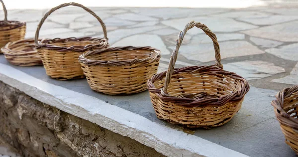 Woven handmade basket for sales on paved street at Cyclades island, Greece. Traditional eco low container from natural rattan with or without handle.