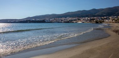 Andros Adası, Neimporio Sahili Chora kasabası, Cyclades Yunanistan. Deniz manzaralı bina, kumlu kozmopolit plaj, parlak deniz, mavi gökyüzü güneşli gün..