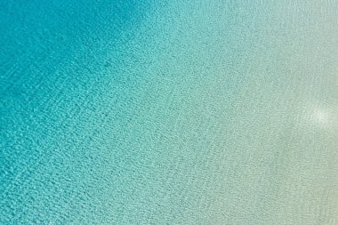 Okyanus turkuazı mavi Ege şeffaf deniz suyu yüzeyi arka plan dokusu, hava aracı görüntüsü. Yunanistan ve yaz güneşli Cyclades Adası.