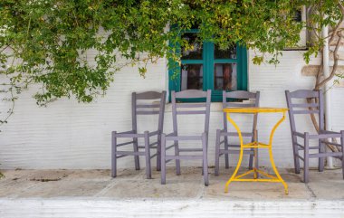 Yunanistan 'da, Tinos Adası Hora kasabası Kiklad' da geleneksel boş bir kafe. Koltuğu olmayan sandalye bina, masa, bitki, yaz tatili. 