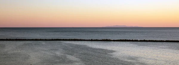 カラフルな空のピンクの紫色のオレンジ 天国の暗い灰色のエーゲ海リップルに対して平和です ティノス島の防波堤キュクラデスギリシャ スペース バナー — ストック写真