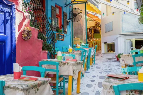 ギリシャの屋外伝統的な居酒屋レストラン ティノス島ホラ町Cyclades 多色の建物 空の椅子テーブル 舗装された路地 — ストック写真