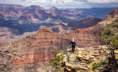 Grand Canyon Ulusal Parkı, Arizona, varış yeri ABD. İnsanoğlu bulutlu bir arka plan altında kırmızı kaya oluşumuna sahip ay manzarasına hayran..