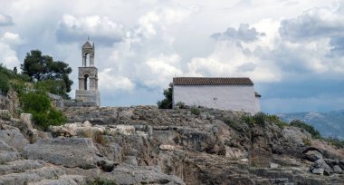 Elefsina Panagia Mezosporitissa küçük eski Ortodoks Kilisesi, Attica Yunanistan 'ın varış noktası olan Arkeoloji Alanı üzerindeki çan kulesi. Bulutlu gökyüzü arkaplanı.