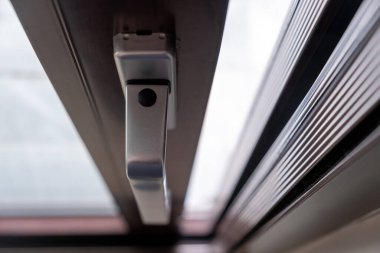 Kapalı pencerenin alüminyum gümüş saplı ve arka planı bulanık. Güvenli kilit mekanizması ile kabzanın üst görüntüsünü kapat.