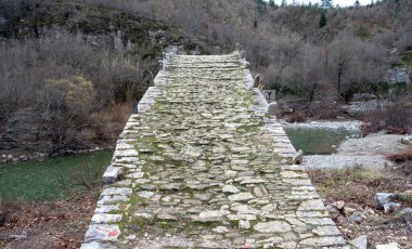 Yunanistan Kalogeriko veya Plakidas Voidomatis nehir suyu üzerindeki antik taş köprü, Zagoria Epirus. Kış ağacının kayalık patikasından görünüm.