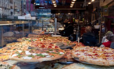 Pizza dükkanı vitrininde pizza çeşitleri, yakın çekim. Lezzetli İtalyan sokak yemekleri. 