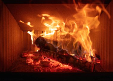 Ateş alevleri ve yanan odun odunları, yakın bir şömine, kışın sıcak bir ev, ön manzara.