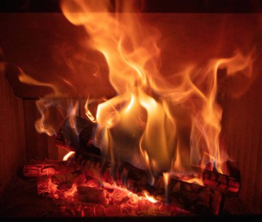 Ateş alevleri ve yanan odun odunları, yakın bir şömine, kışın sıcak bir ev, ön manzara.