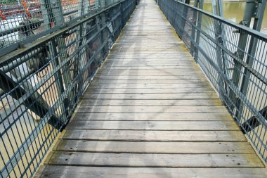 Almanya 'nın Heidelberg şehrinde Neckar Nehri üzerinde demir parmaklıklı bir köprü. Boş tahta yaya köprüsü yolu güneşli bir gün. Nehir suyunun üstünde.