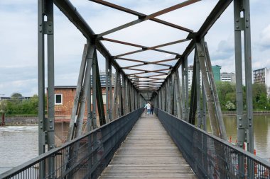Neckar Nehri üzerindeki metal şablon köprüsü, mavi gökyüzü arkaplanı. Almanya 'nın Heidelberg şehrinde insanlar tahta yaya köprüsünden geçiyorlar..