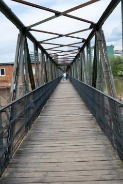 Neckar Nehri üzerindeki metal şablon köprüsü, mavi gökyüzü arkaplanı. Almanya 'nın Heidelberg şehrinde insanlar tahta yaya köprüsünden geçiyorlar..